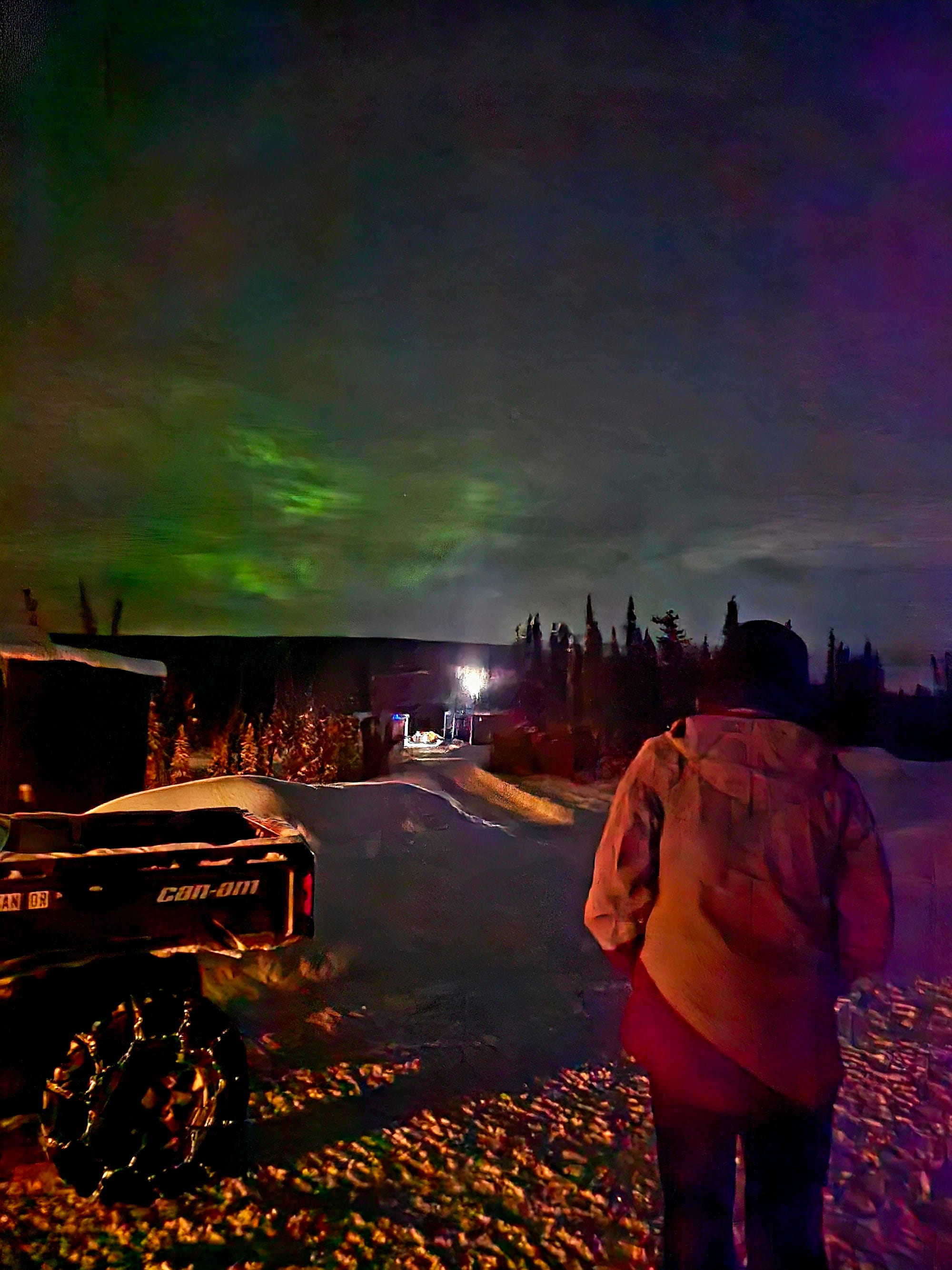 Waiting under the same green aurora — boots in the snow, cabin lights behind us, and the Interior Alaska cold settling in while the sky quietly moved overhead.