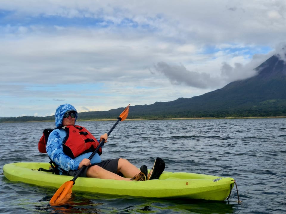 Kayaking on Lake Arenal with Arenal Volcano dominating the backdrop — calm water, scale, and a clear sense of place.